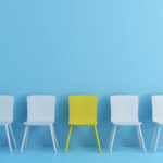 یک صندلی زرد بین صندلی های آبی به نشانه شغل رویایی